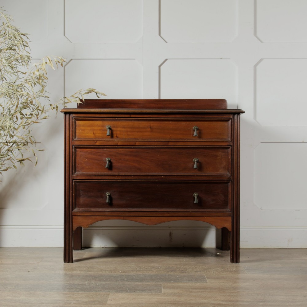 An Edwardian mahogany chest featuring three graduated drawers with drop handles, fluted side pilasters, and a low upstand. View II