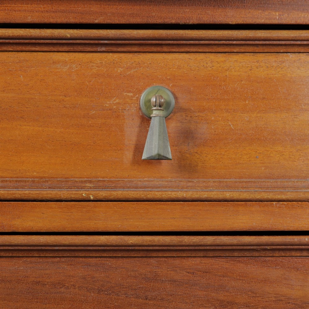 An Edwardian mahogany chest featuring three graduated drawers with drop handles, fluted side pilasters, and a low upstand. View IV