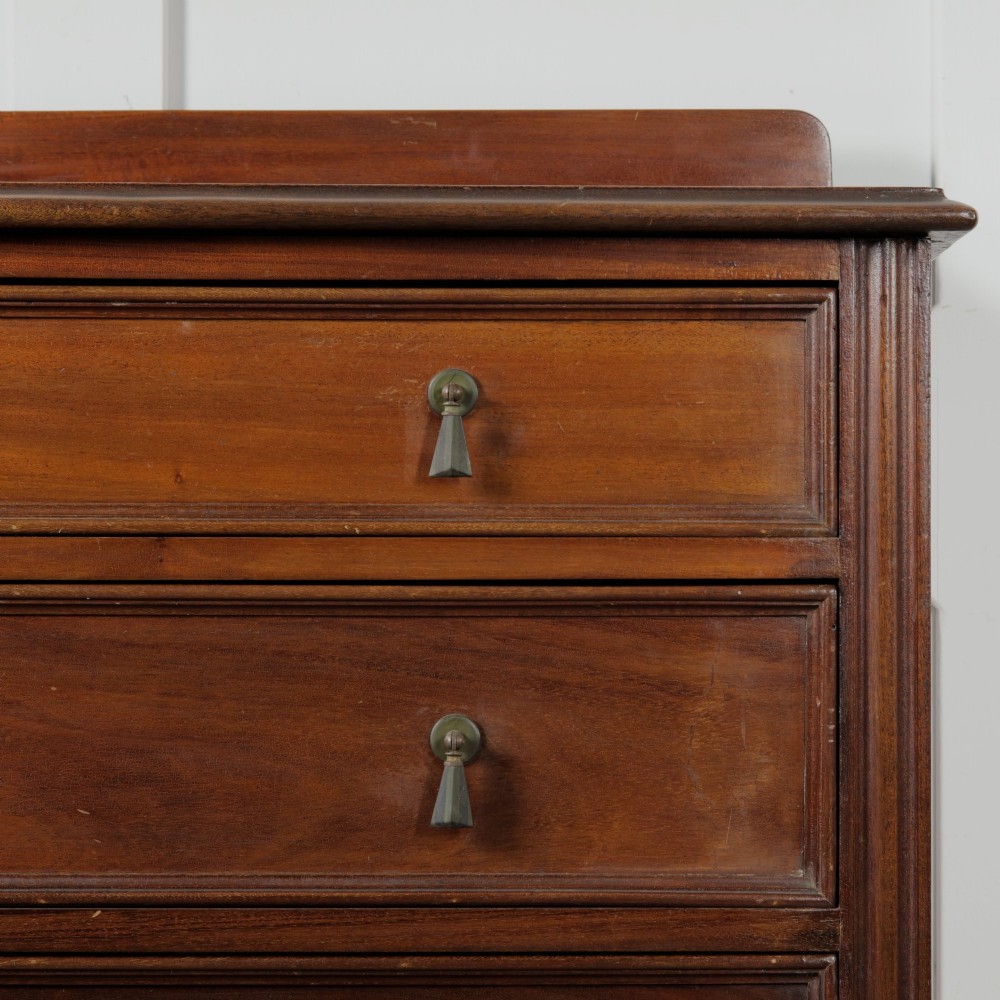 An Edwardian mahogany chest featuring three graduated drawers with drop handles, fluted side pilasters, and a low upstand. View V