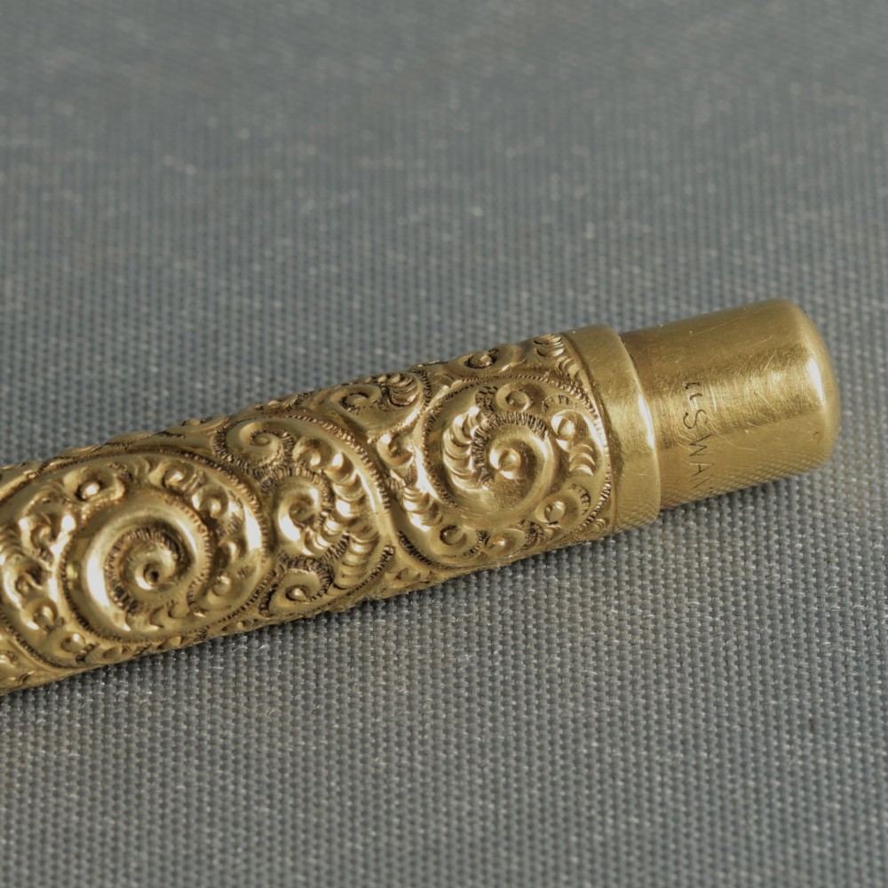 An antique Mabie Todd Swan fountain pen with a detailed chased rolled gold barrel, unscrewed cap, and dark ebonite section with exposed nib. View IV