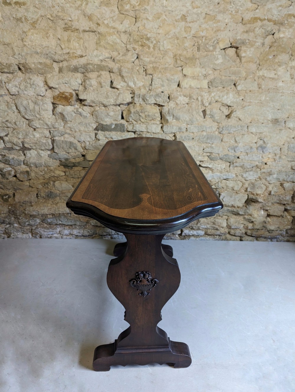 A late 19th-century dark oak trestle table featuring a shaped top with contrasting inlaid border and a low stretcher with a central carved boss. View IV