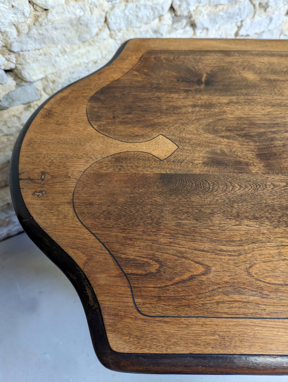 A late 19th-century dark oak trestle table featuring a shaped top with contrasting inlaid border and a low stretcher with a central carved boss. View VI