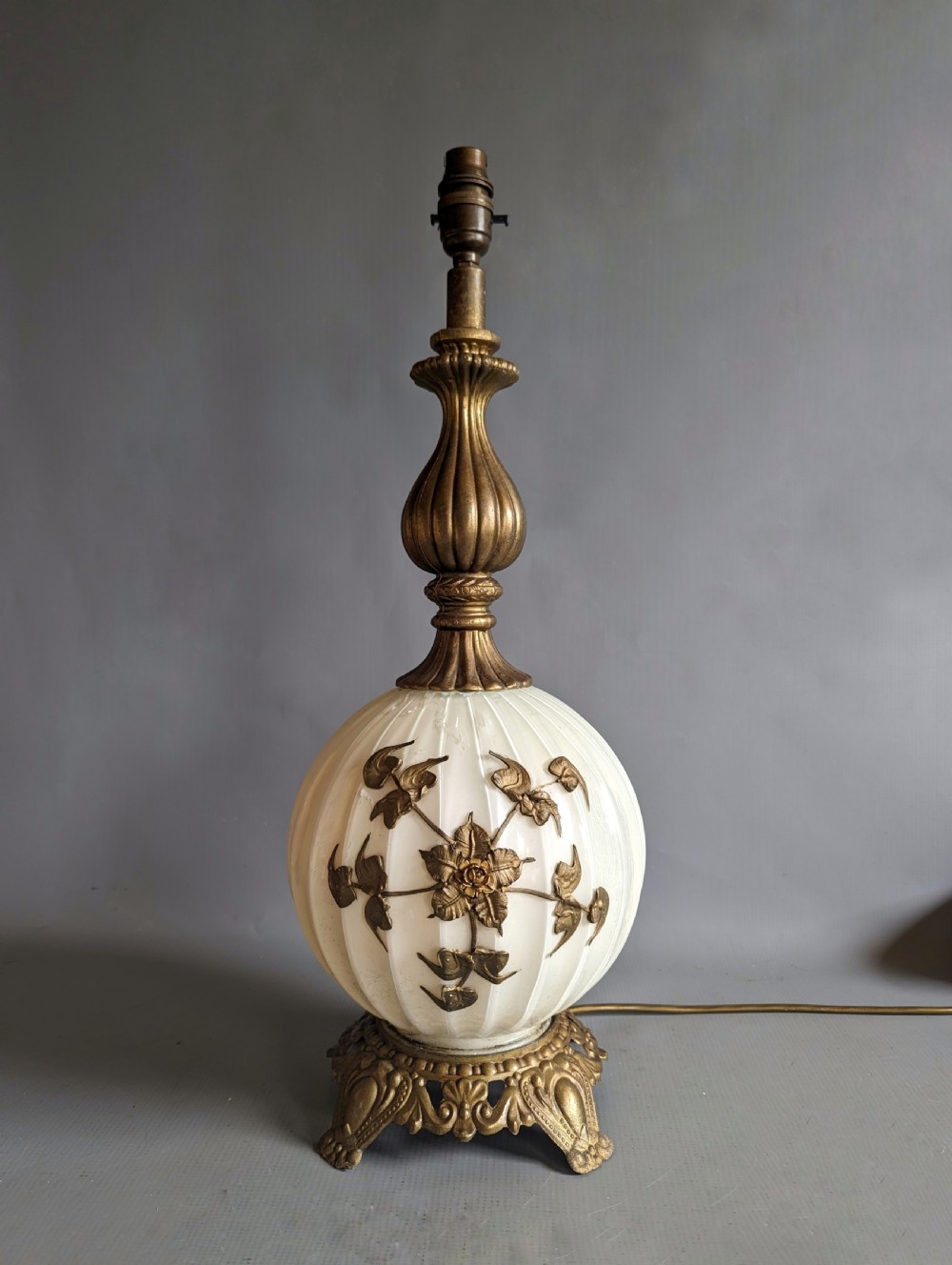 A white ribbed opaline glass table lamp featuring cast brass floral appliques, an ornate footed base, and a fluted metal neck.