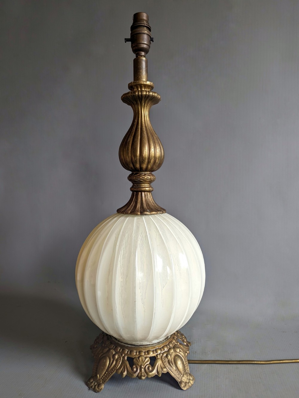 A white ribbed opaline glass table lamp featuring cast brass floral appliques, an ornate footed base, and a fluted metal neck. View V