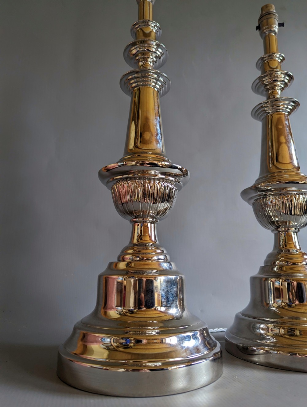 A pair of polished silver-toned metal table lamp bases featuring stepped circular bases and turned baluster columns. View V