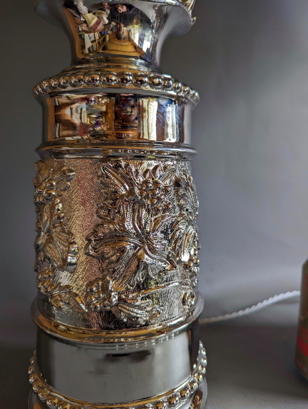 A pair of reflective nickel-plated table lamps featuring embossed foliate relief, scroll handles, and beaded rim details. View II