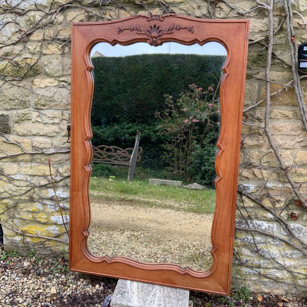 A rectangular French timber wall mirror featuring a carved shell cresting motif and a scalloped inner frame moulding.