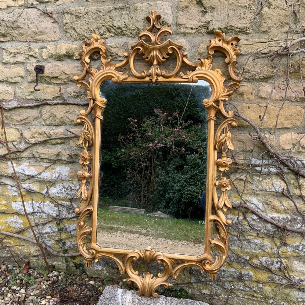 An early 19th-century rectangular mirror set within a gold giltwood frame featuring carved acanthus leaves, scrollwork, and floral motifs.
