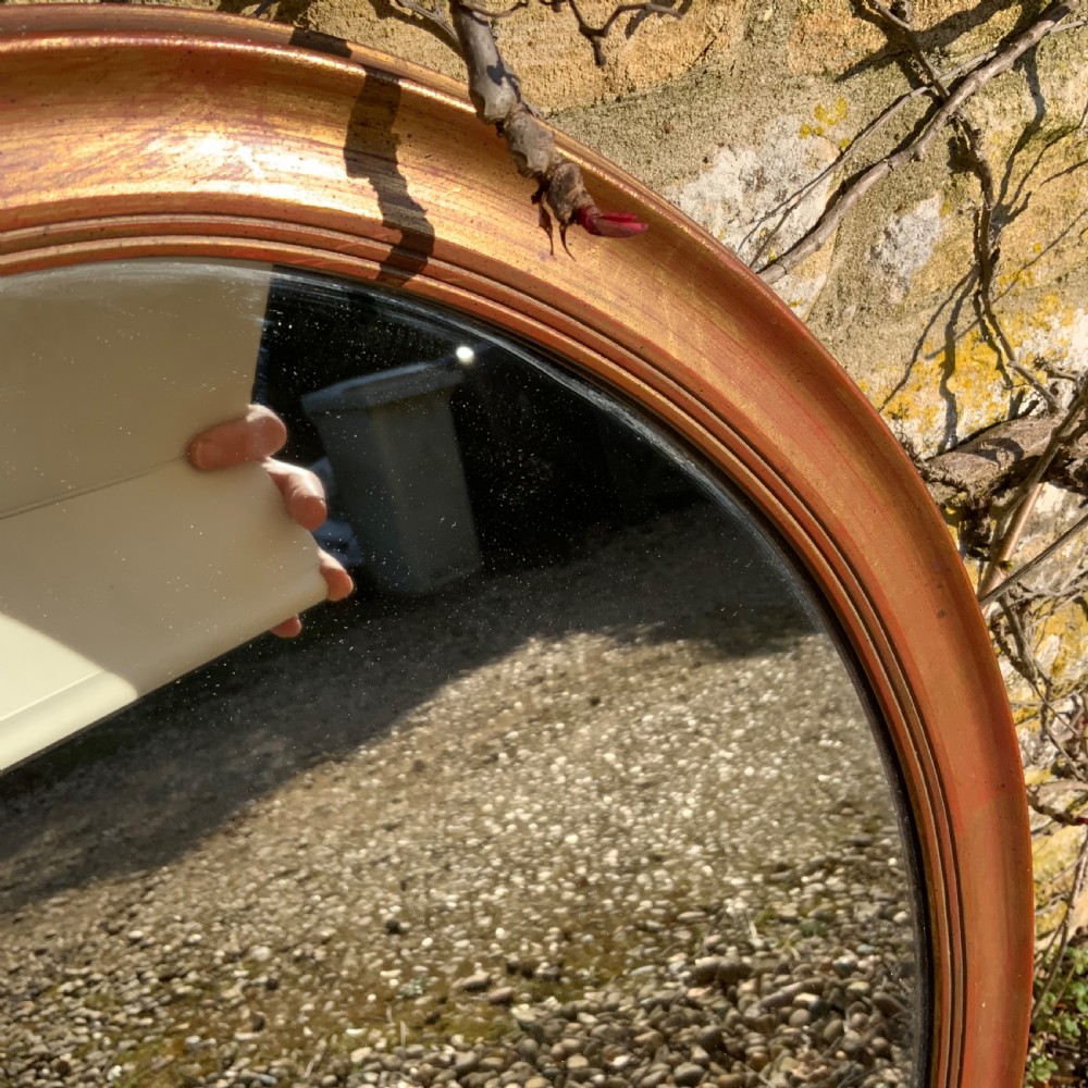 An antique oval wall mirror featuring a moulded gilt frame and reflective glass plate. View II