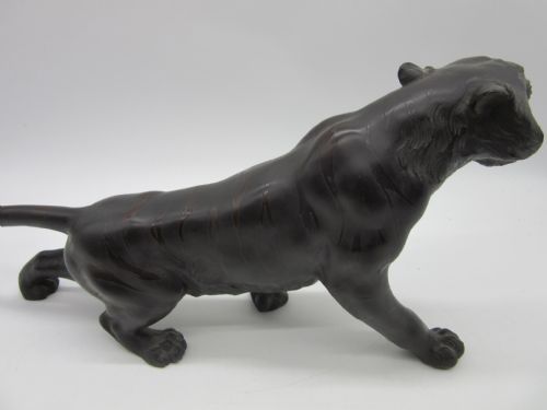 fig 1. A dark patinated bronze sculpture of a tiger depicting a prowling pose with an open roaring mouth and raised tail.