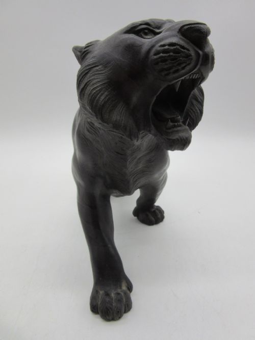 fig 2. A dark patinated bronze sculpture of a tiger depicting a prowling pose with an open roaring mouth and raised tail.