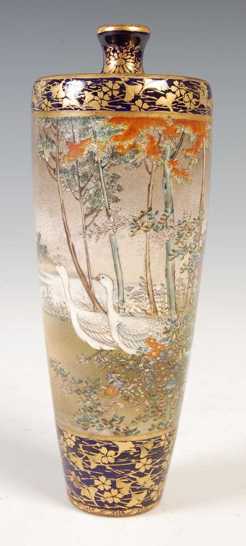 fig 1. A tall Japanese Satsuma ceramic vase featuring detailed polychrome floral paintings on a cream crackle ground flanked by dark cobalt blue and gilt bands.