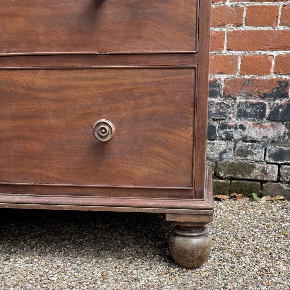 An antique mahogany chest of drawers featuring three short drawers over three long graduated drawers with turned wooden knobs and bun feet. View II