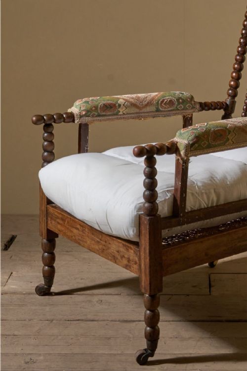 fig 1. A 19th-century bobbin-turned armchair featuring simulated rosewood timber, patterned armrest upholstery, a white seat cushion, and brass castors.