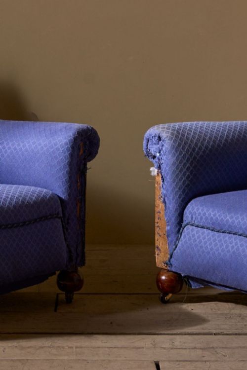fig 1. A pair of vintage Art Deco club armchairs upholstered in blue patterned fabric featuring turned wooden feet with castors.
