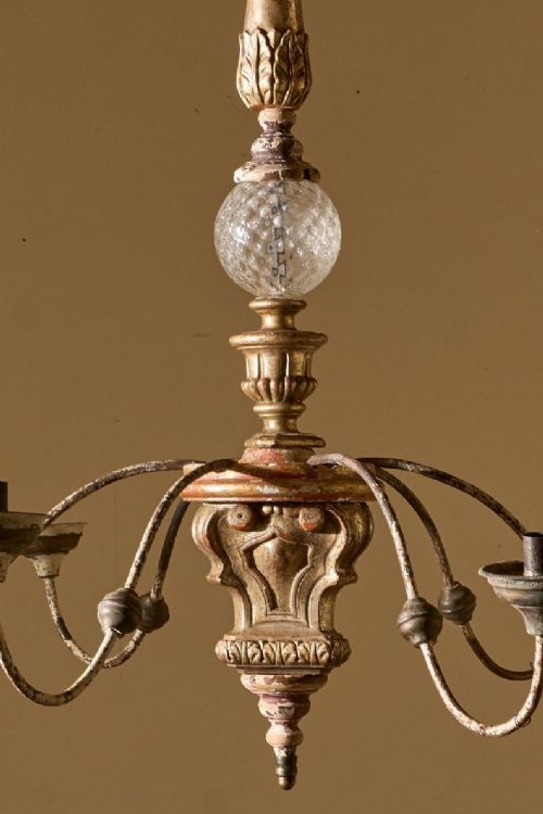 fig 1. A nineteenth-century pricket candle chandelier featuring a carved giltwood stem, central glass orb, and curved iron arms holding drip pans with prickets.