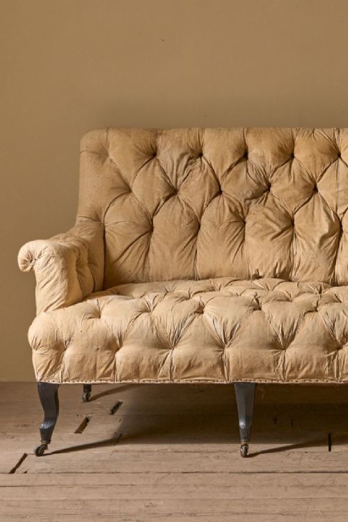 fig 1. A 2.1-metre Napoleon III sofa with deep buttoned beige upholstery, turned black legs, and brass castors.