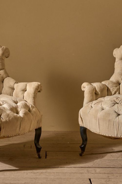 fig 1. A pair of French Napoleon III armchairs featuring deep-buttoned calico upholstery, flared backrests, and dark turned legs on brass castors.