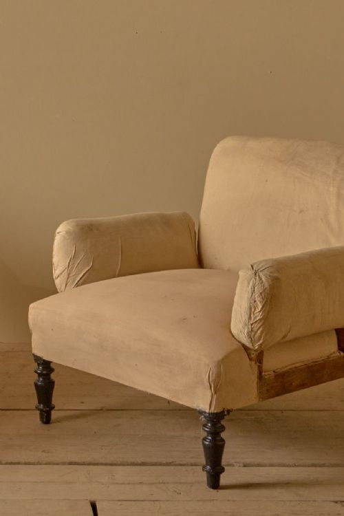 fig 1. A pair of 19th-century French Napoleon III armchairs upholstered in neutral calico fabric with padded pillow arms and dark turned front legs.