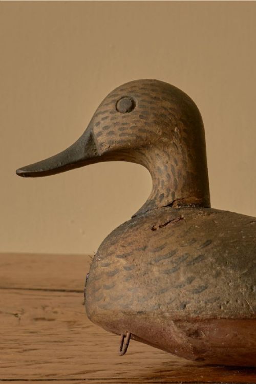 fig 2. A hand-carved early 20th-century wooden decoy duck featuring distressed brown painted plumage detail on a timber surface.