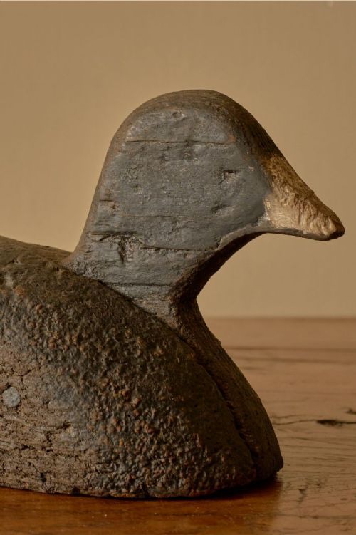 fig 2. A carved wooden decoy duck with a weathered dark brown finish and tapered beak.