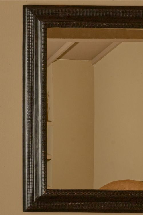 fig 1. A rectangular 19th-century Italian wall mirror featuring a dark ebonised wooden frame with textured carved moulding.
