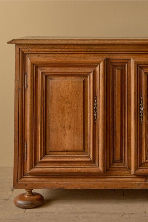fig 1. An 18th-century Dutch oak cupboard featuring two fielded panel doors, central moulded detail, and turned bun feet against a neutral wall.
