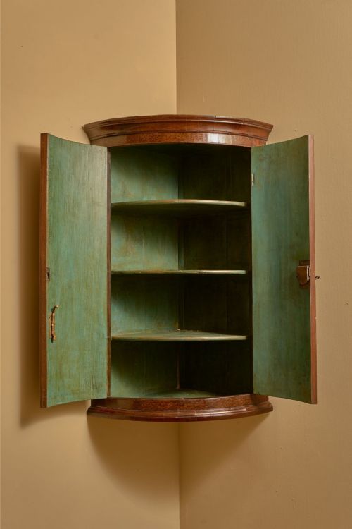 fig 1. A wall-hanging Georgian bow-front corner cupboard made from rich warm brown plum pudding mahogany with double doors and brass H-hinges.