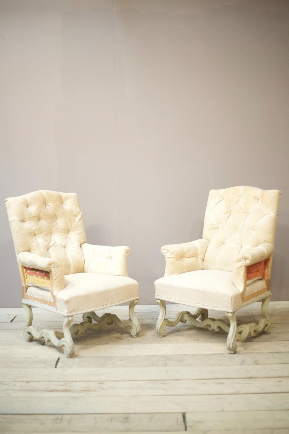 Pair of French buttoned armchairs with carved frame
