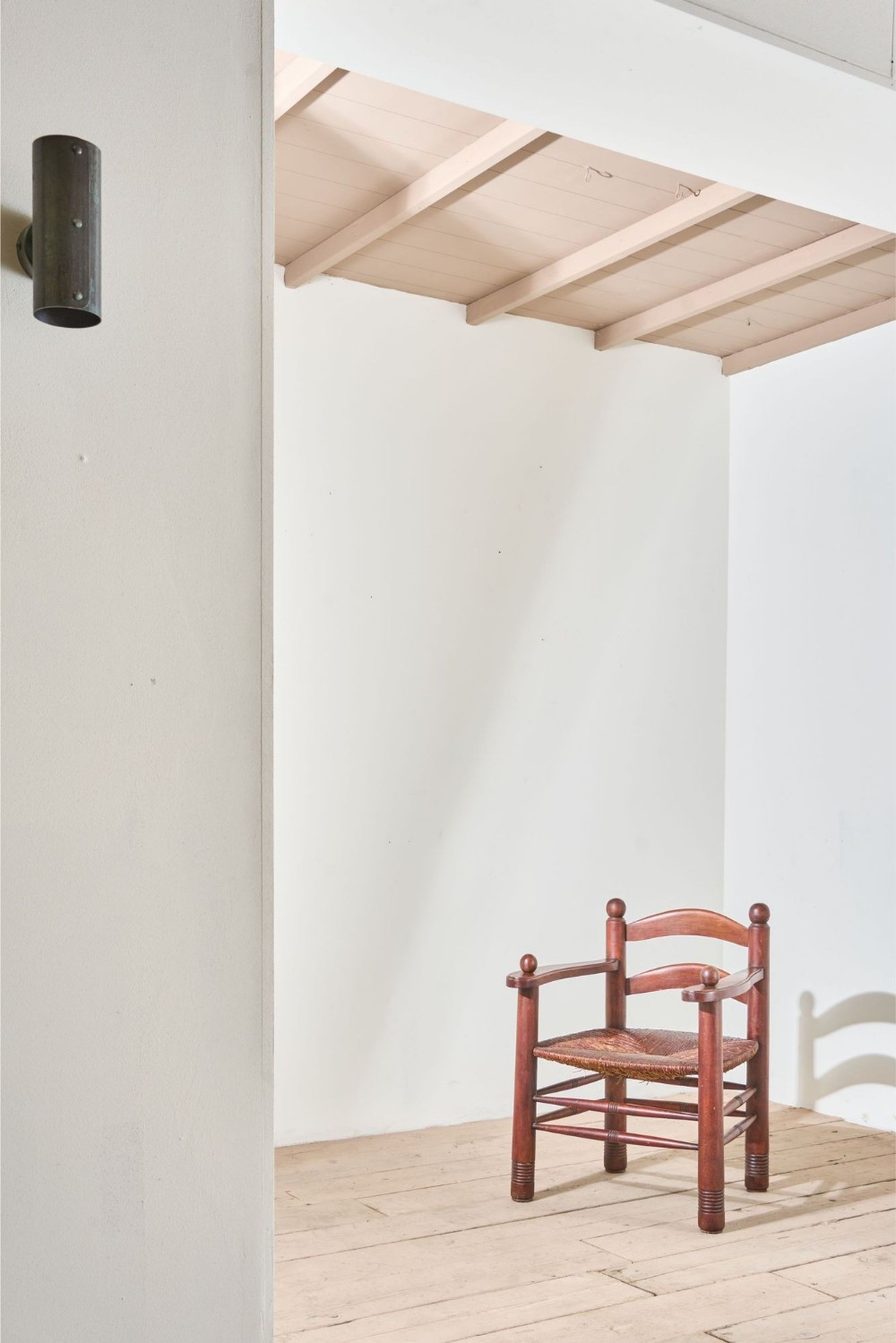 A low Charles Dudouyt French modernist armchair made from turned oak wood with a woven rush seat and spherical post finials.