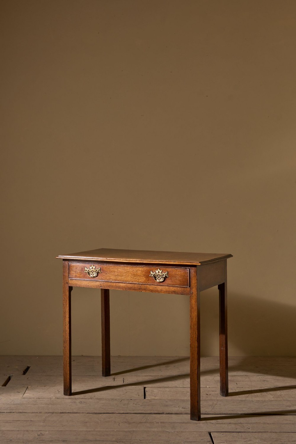 An 18th-century oak side table featuring a single full-width drawer with two brass handles, supported by four straight legs.