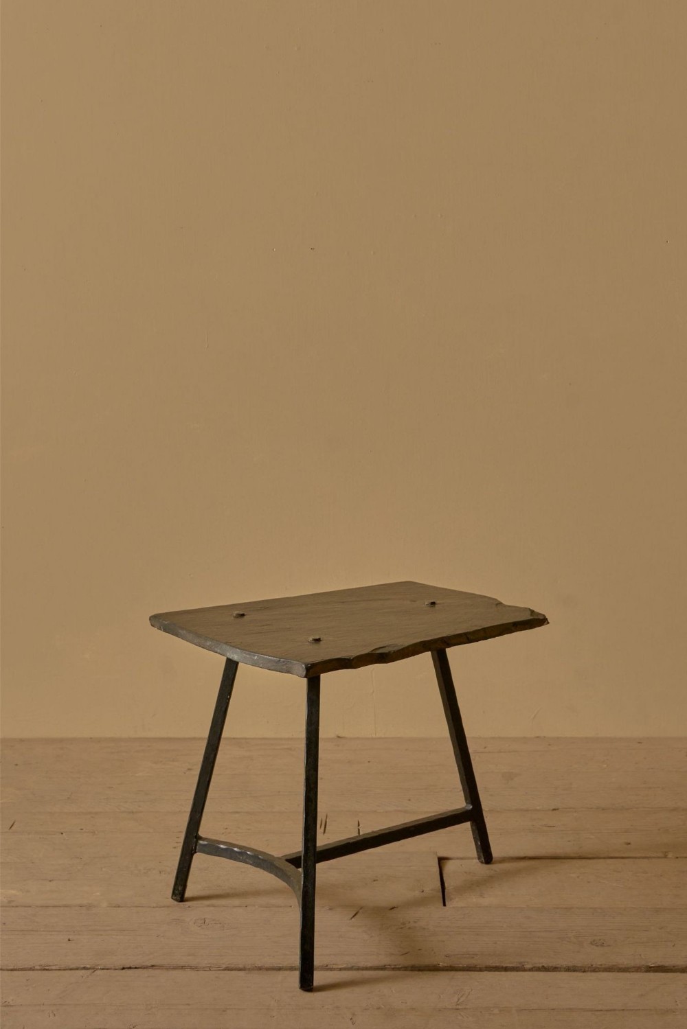 A mid-century French side table featuring a dark slate top with exposed bolt fixings supported by a slender dark steel leg frame.