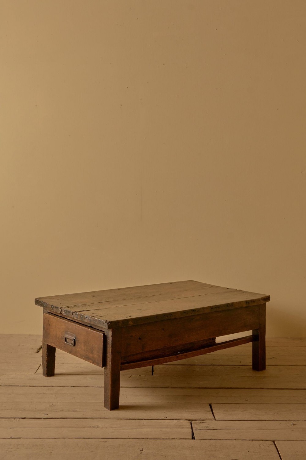 An eighteenth-century French provincial walnut low table featuring a thick plank top, square legs, and an integrated end drawer with a metal pull handle.