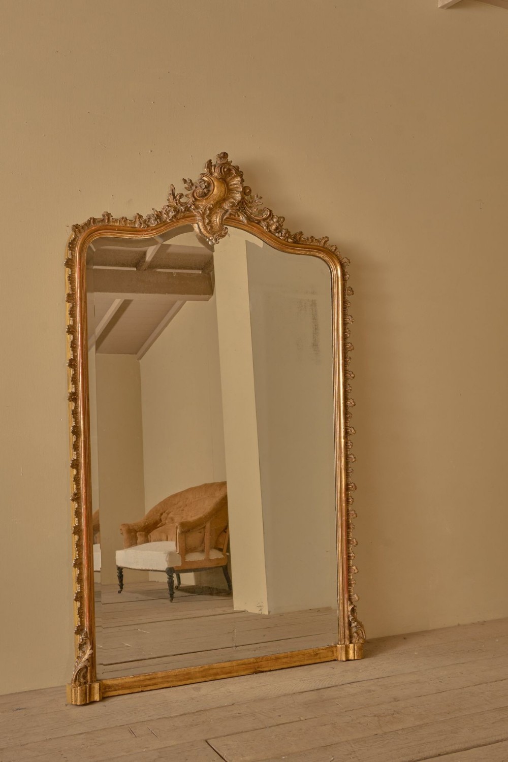 A large 19th-century arched overmantel mirror with a gold leaf frame and central carved shell cresting.