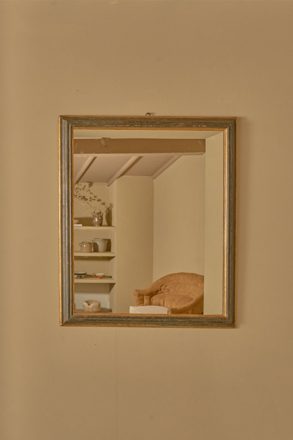 A rectangular wall mirror featuring a dark grey faux marble painted wooden frame bordered with a gold leaf inner moulding.