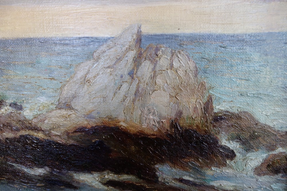 An early 20th-century impressionist oil painting depicting waves crashing against rocky coastal cliffs under cloudy grey skies, enclosed in a dark molded wooden frame with a gilded inner border. View V