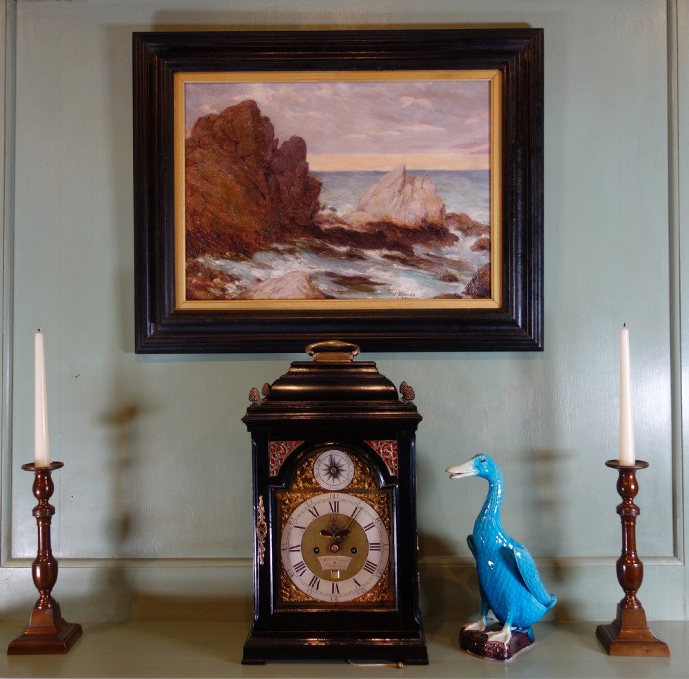 An early 20th-century impressionist oil painting depicting waves crashing against rocky coastal cliffs under cloudy grey skies, enclosed in a dark molded wooden frame with a gilded inner border. View VI