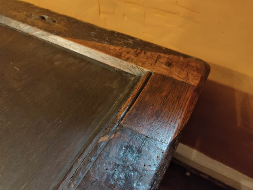 A dark oak 17th-century coffer featuring three carved front panels with diamond lozenges and a carved top frieze below a panelled hinged lid. View III