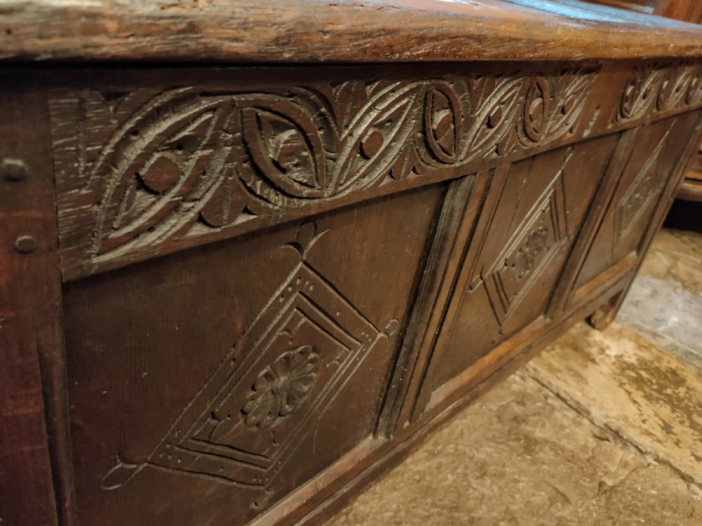 A dark oak 17th-century coffer featuring three carved front panels with diamond lozenges and a carved top frieze below a panelled hinged lid. View IV