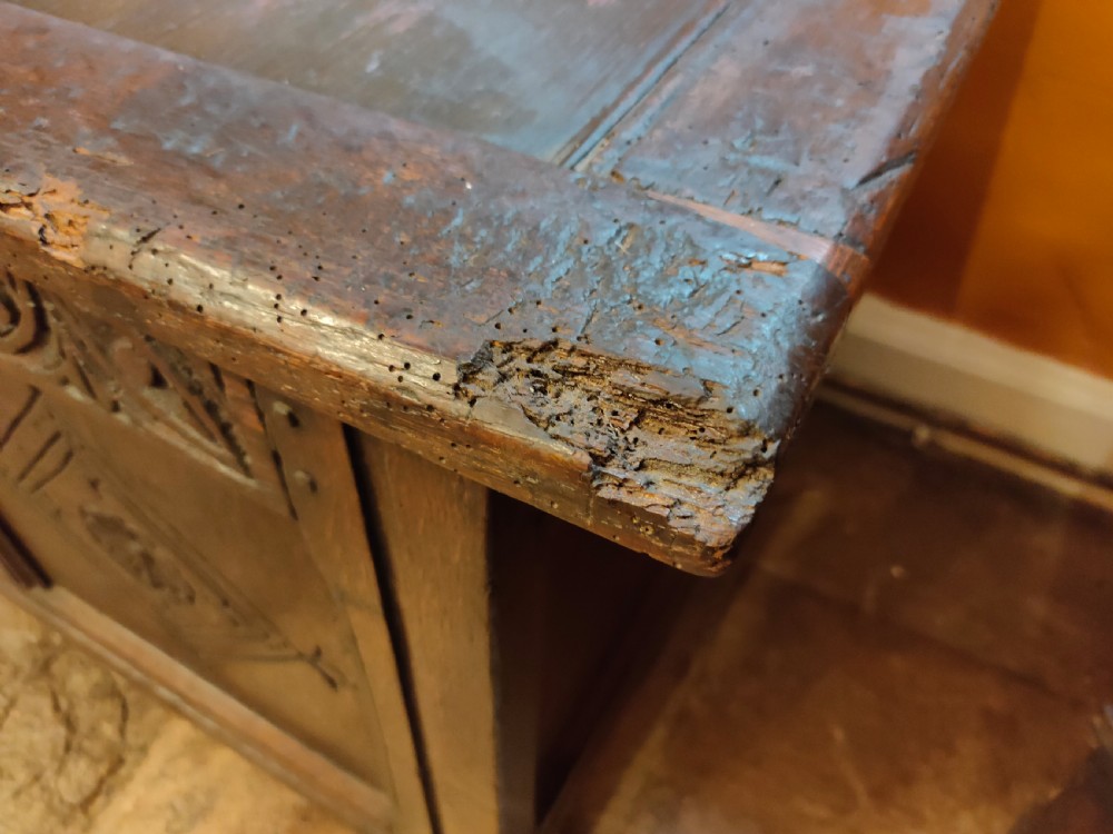 A dark oak 17th-century coffer featuring three carved front panels with diamond lozenges and a carved top frieze below a panelled hinged lid. View VII
