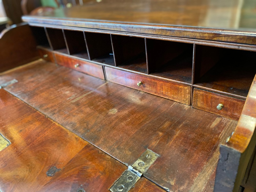 Mid 18th-century walnut kneehole secretaire desk featuring crossbanded drawer fronts, brass drop handles, a central recessed cupboard, and bracket feet. View III