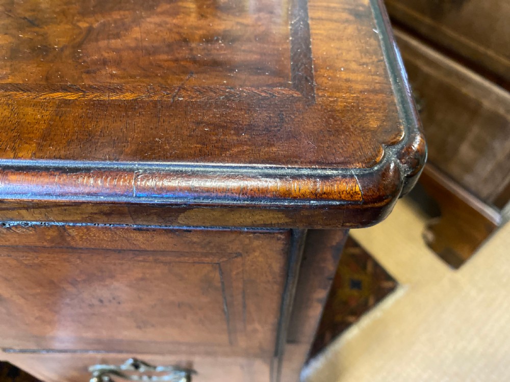 Mid 18th-century walnut kneehole secretaire desk featuring crossbanded drawer fronts, brass drop handles, a central recessed cupboard, and bracket feet. View V
