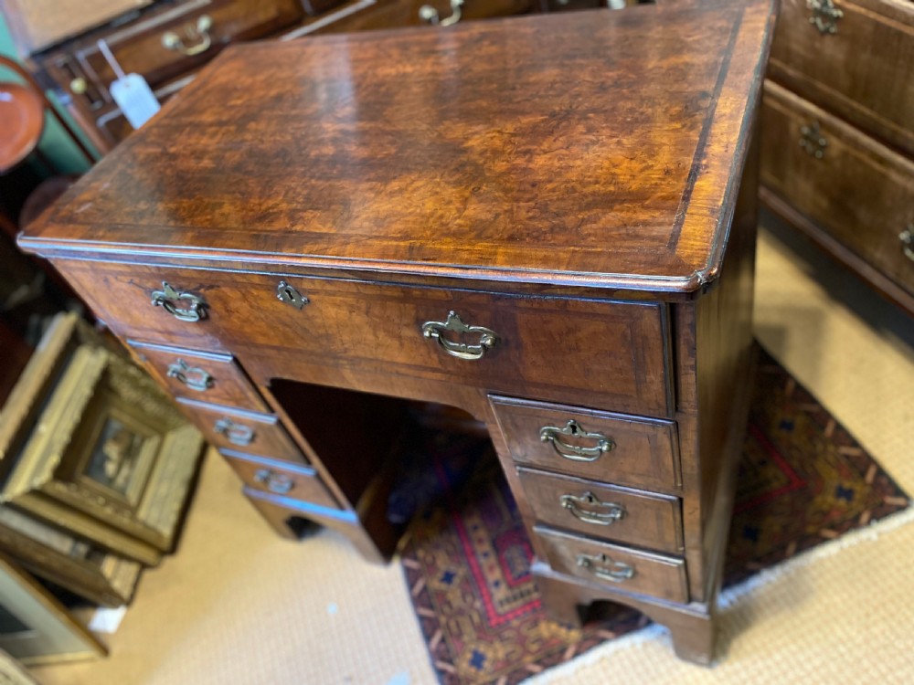 Mid 18th-century walnut kneehole secretaire desk featuring crossbanded drawer fronts, brass drop handles, a central recessed cupboard, and bracket feet. View VIII