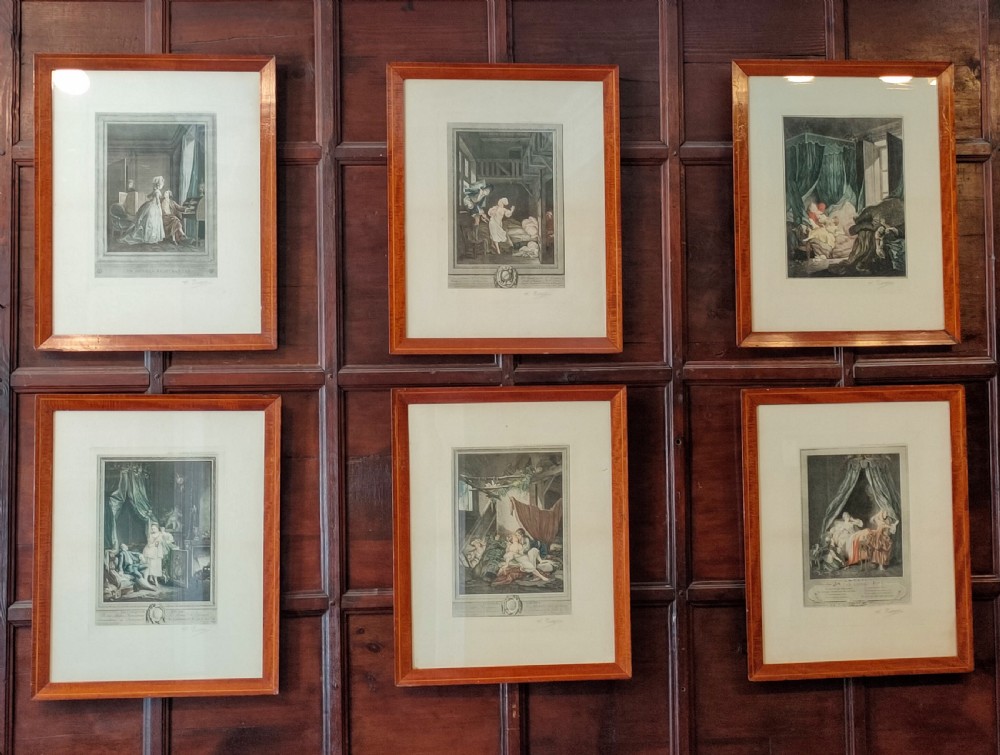 A set of six framed coloured mezzotint engravings depicting eighteenth-century French interior genre scenes, mounted in timber frames.