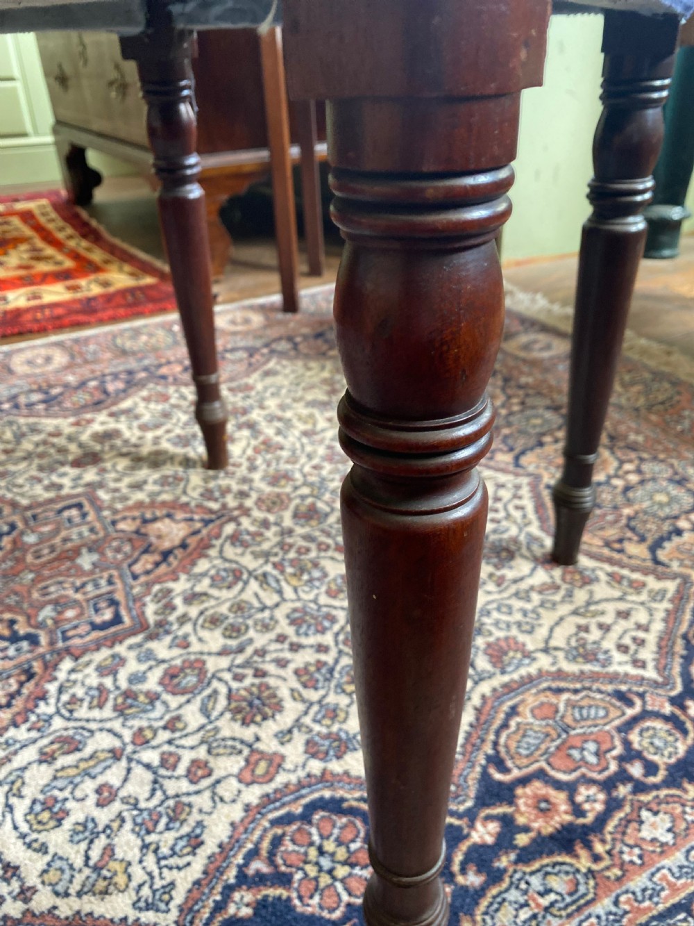 A square Regency stool upholstered in cream patterned fabric with dark turned mahogany legs. View II