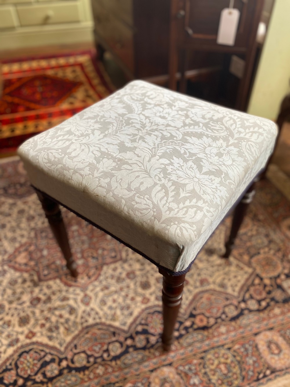 A square Regency stool upholstered in cream patterned fabric with dark turned mahogany legs. View III