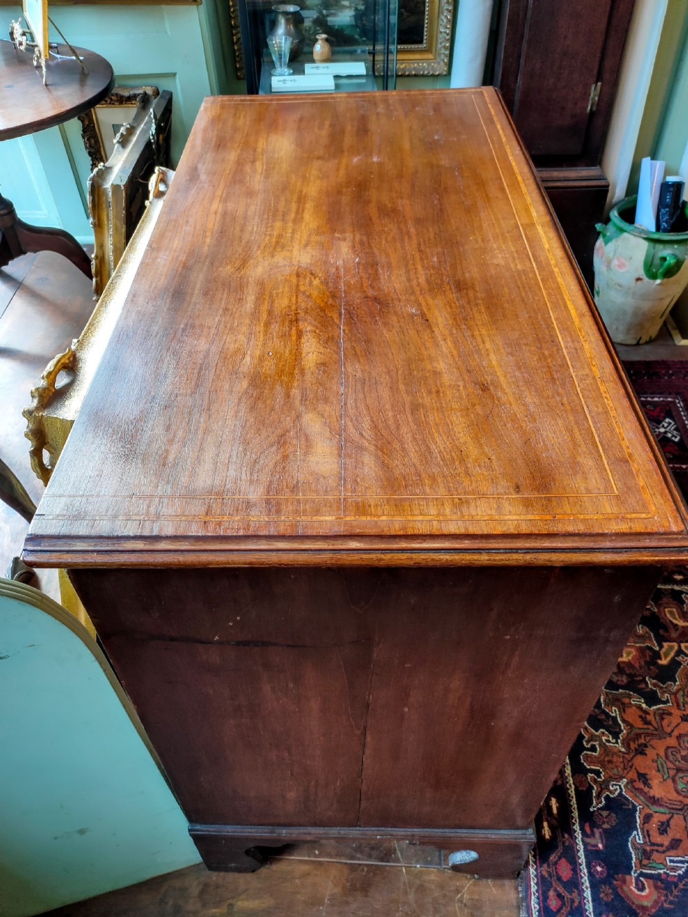 A late eighteenth-century mahogany chest of three drawers featuring fine boxwood stringing inlay, brass swan-neck handles, keyhole escutcheons, and bracket feet. View IV