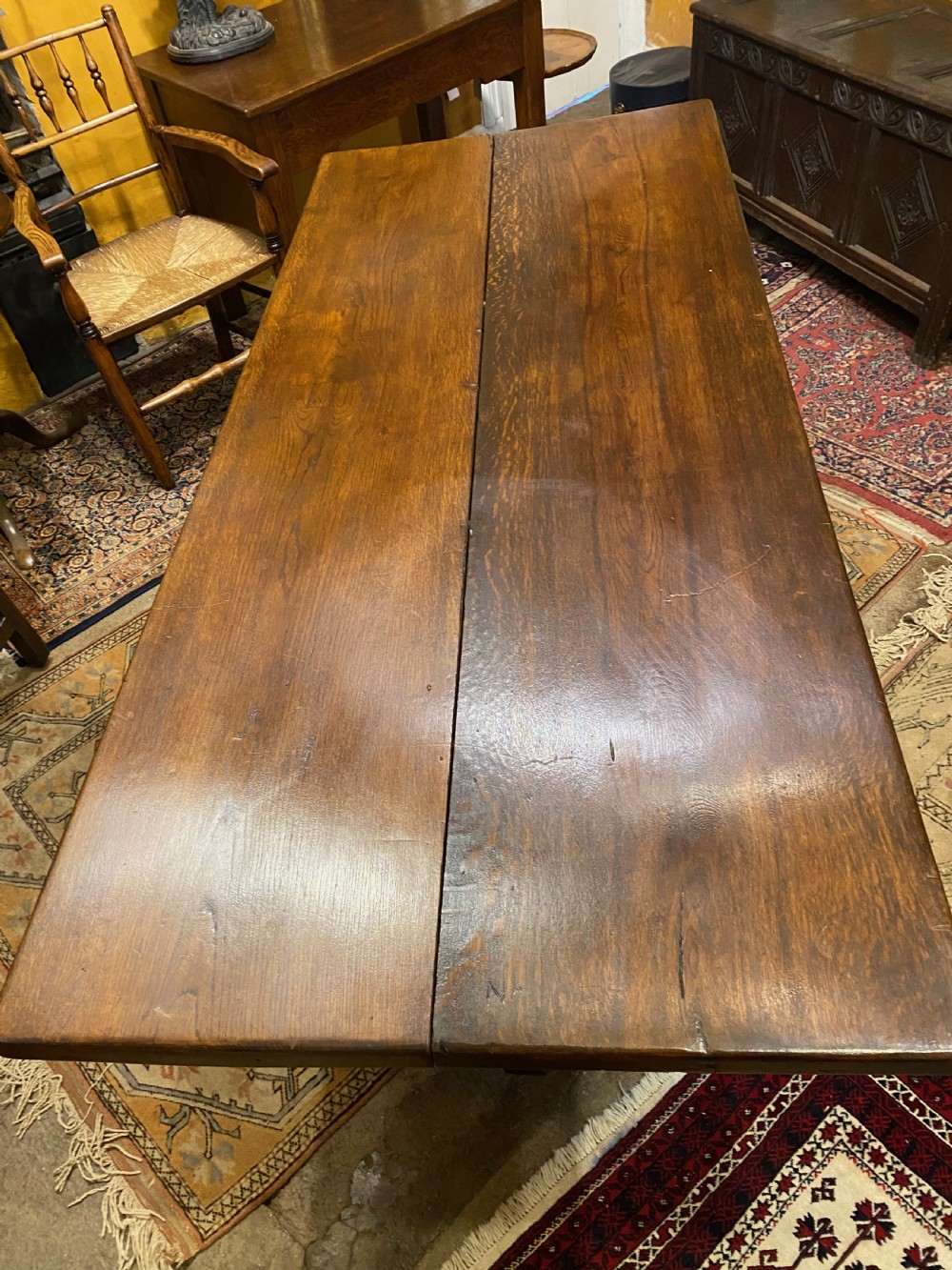 An early nineteenth-century solid oak refectory table featuring a two-plank top supported by shaped trestle end supports and a central stretcher. View II