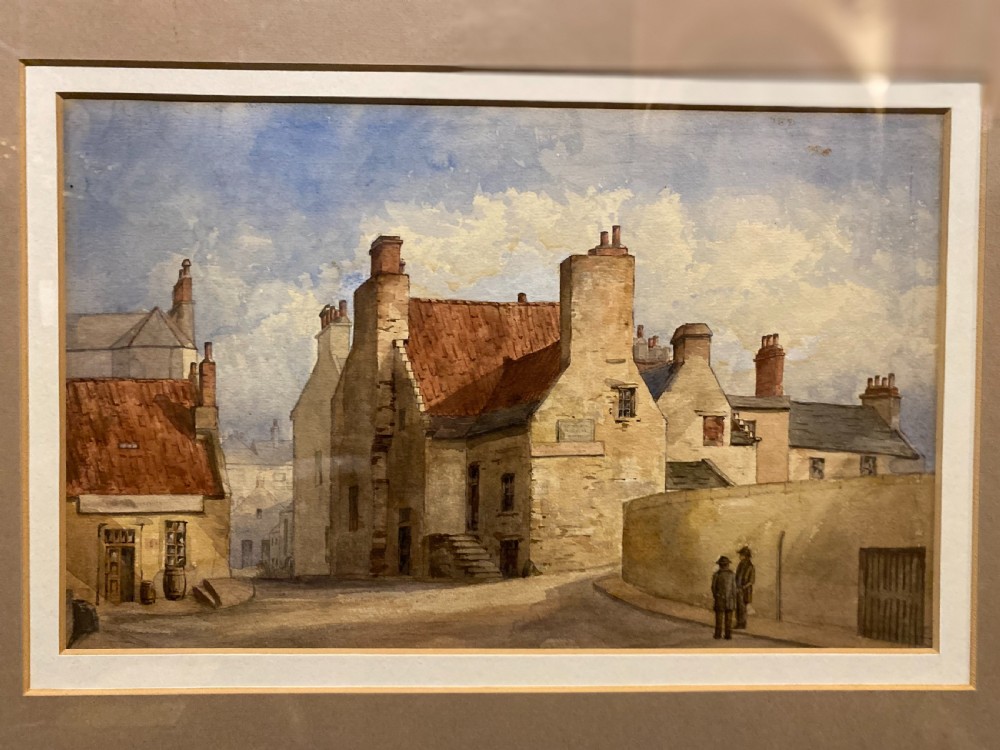 A framed watercolour painting depicting stone village houses with red-tiled roofs along a quiet street under a cloud-filled sky. View III