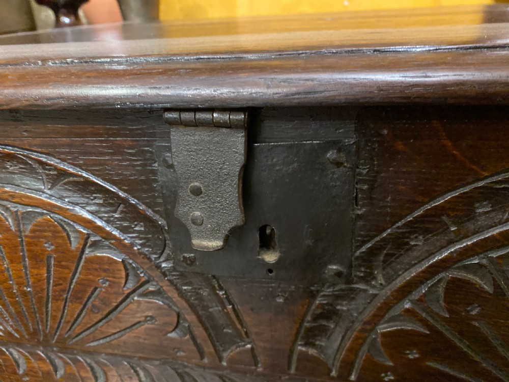 A dark oak wooden bible box featuring a flat hinged top, an iron lock plate, and hand-carved demi-lune fan motifs across the front panel. View III